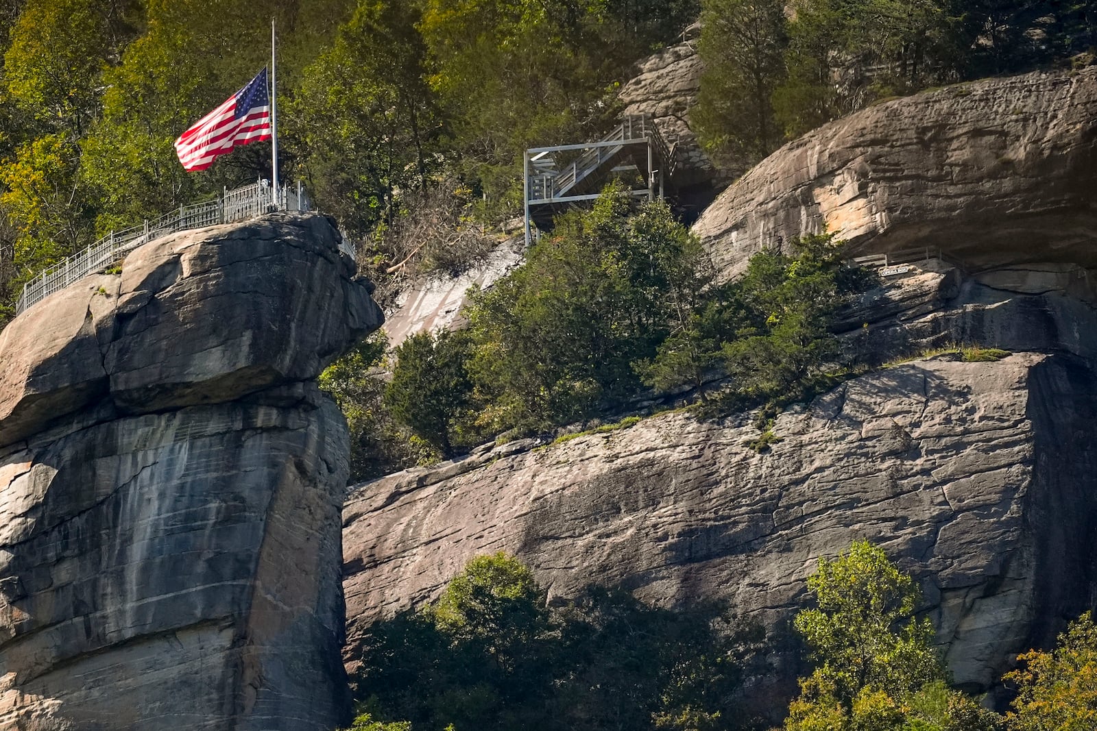 An American flag flies half-staff on top of Chimney Rock mountain in the aftermath of Hurricane Helene, Wednesday, Oct. 2, 2024, in Chimney Rock Village, N.C. (AP Photo/Mike Stewart)