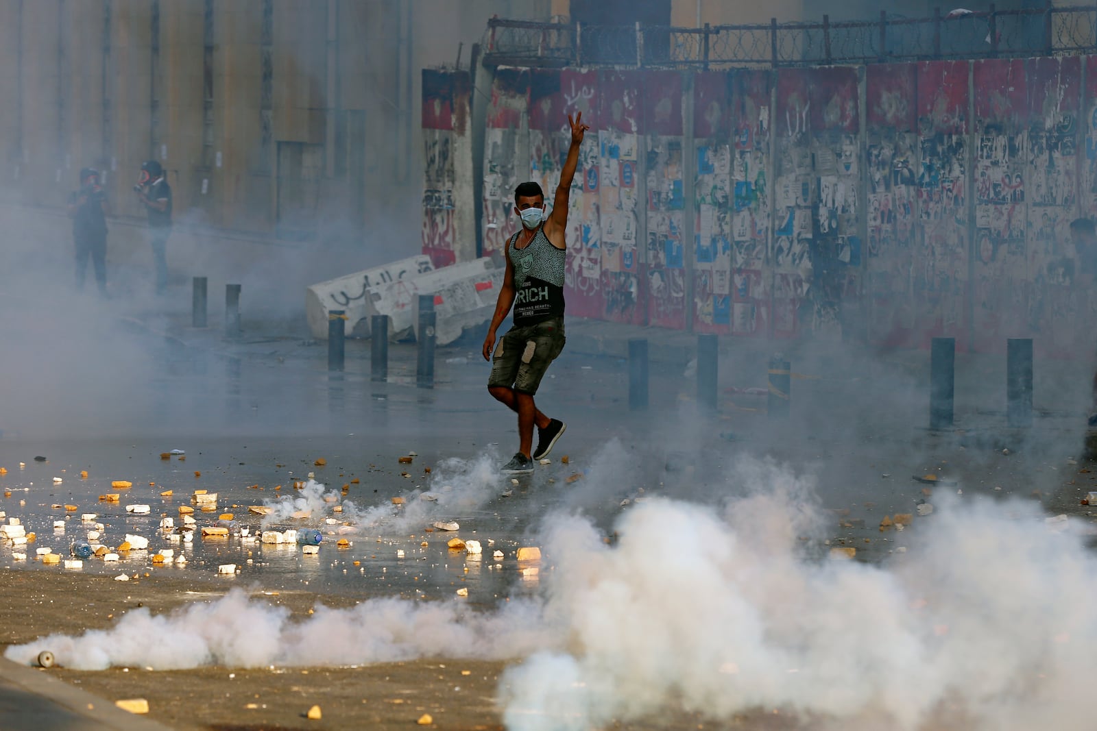 FILE - An anti-government protester flashes the victory sign amid tear gas fired by riot police during a protest marking the first anniversary of the massive blast at Beirut's port, near Parliament Square, in Beirut, on Aug. 4, 2021. (AP Photo/Bilal Hussein, File)