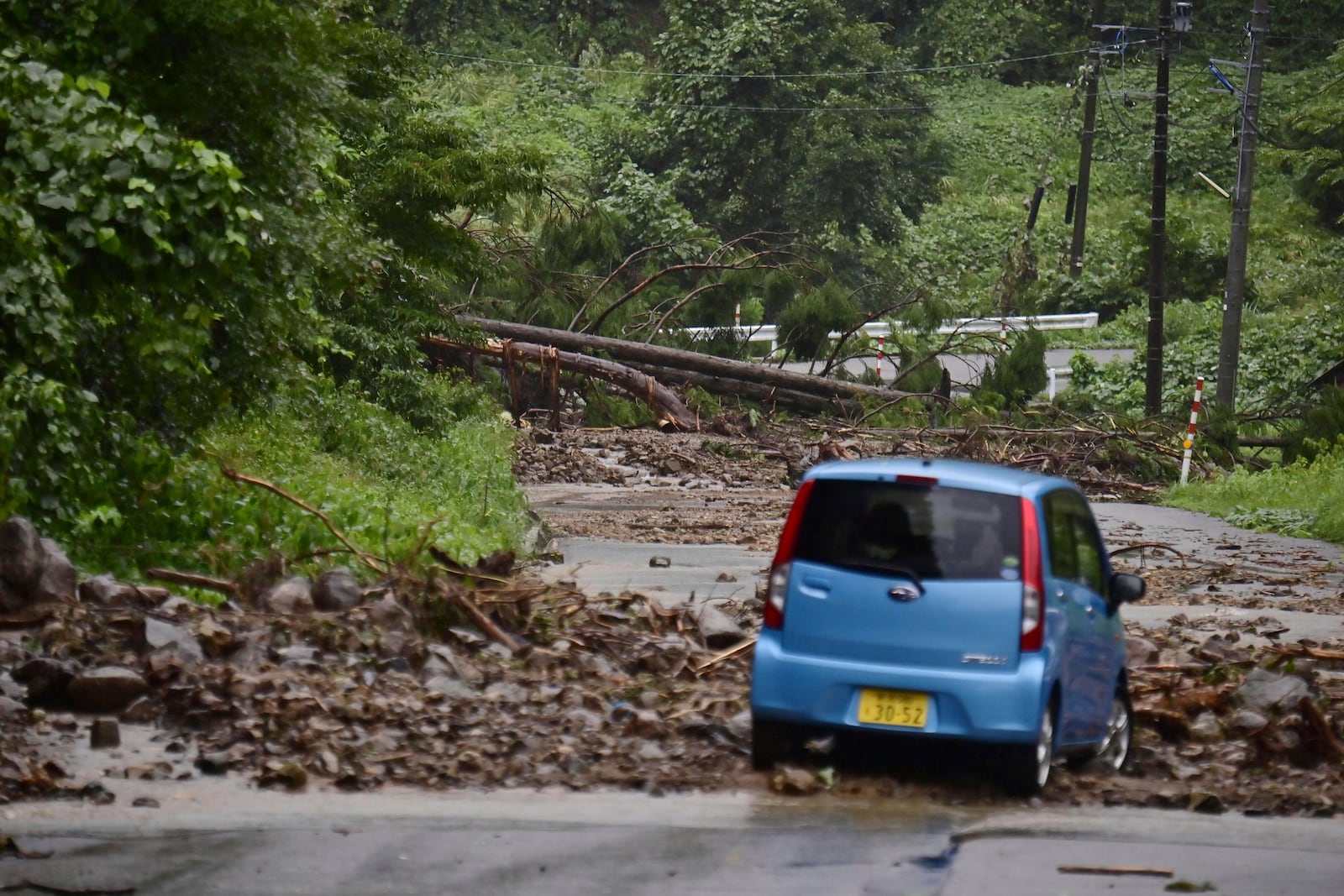 A car is blocked by rocks covering a road, after heavy rain in Wajima, Ishikawa prefecture, Saturday, Sept. 21, 2024. (Kyodo News via AP)