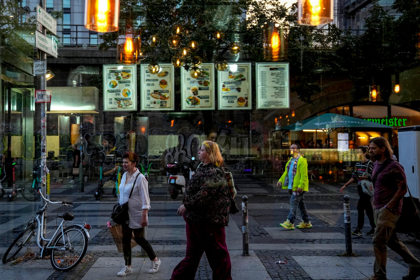 People are seen through the window of a doner kebab restaurant in Berlin, Germany, Wednesday, Sept. 18, 2024. (AP Photo/Ebrahim Noroozi)