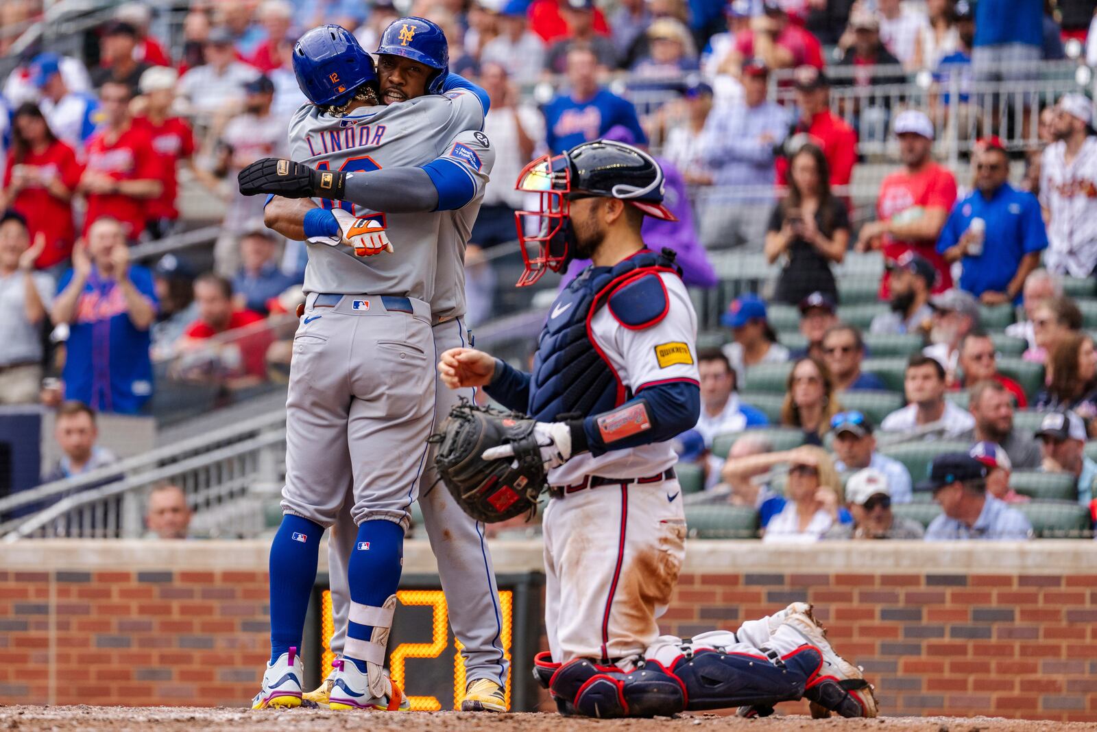 New York Mets' Francisco Lindor, left, and Starling Marte, center, celebrate at home plate after scoring in the ninth inning of a baseball game against the Atlanta Braves, Monday, Sept. 30, 2024, in Atlanta. (AP Photo/Jason Allen)