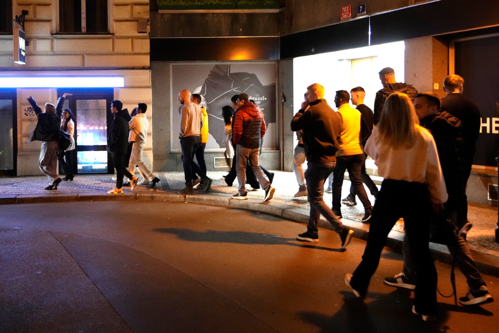 A group of tourists stand in line outside a bar as they attend a pub crawl tour in downtown Prague, Czech Republic, Thursday, Oct. 17, 2024. (AP Photo/Petr David Josek)