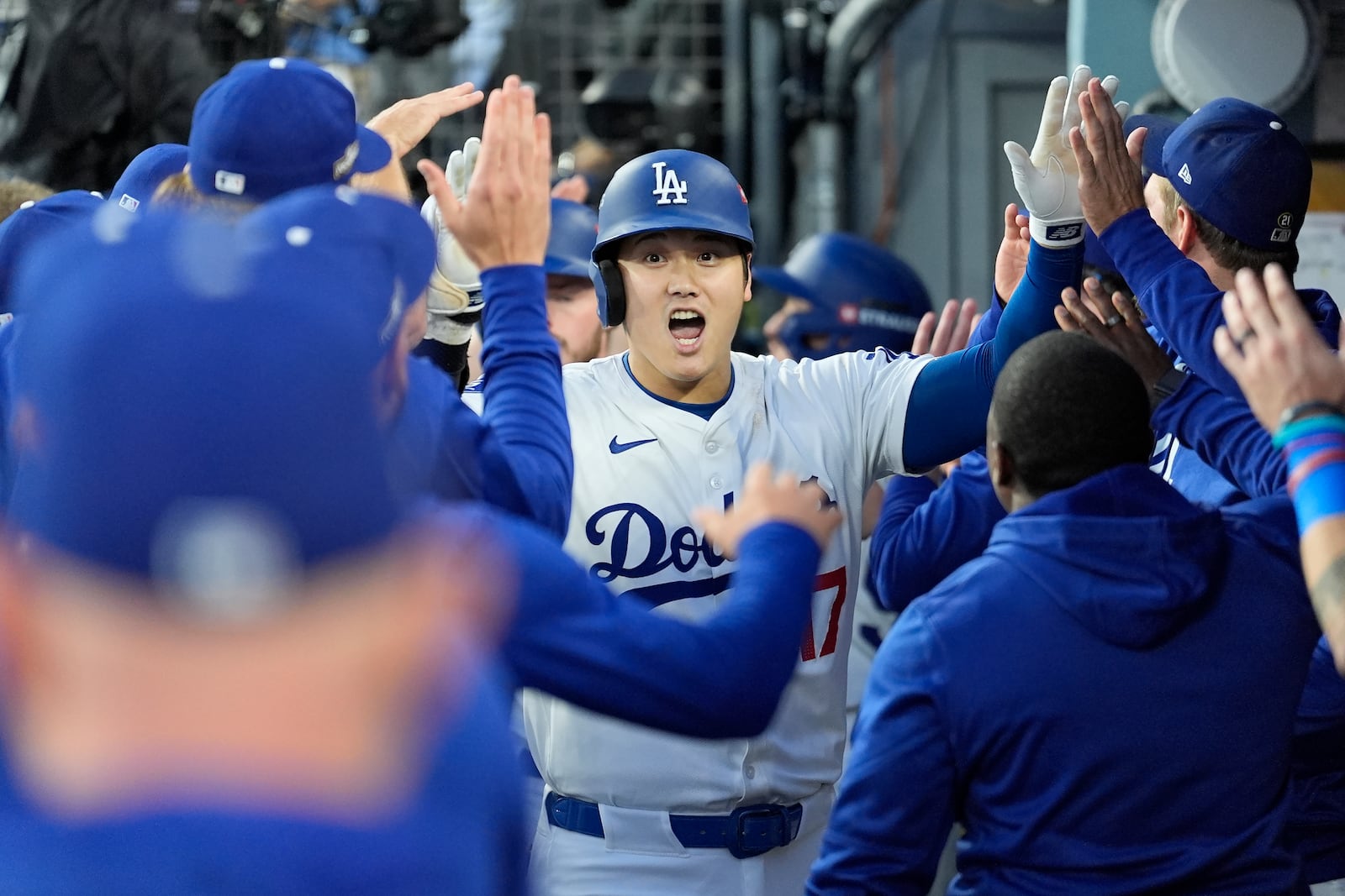 Los Angeles Dodgers' Shohei Ohtani, middle, celebrates with teammates in the dugout after hitting a three-run home run during the second inning in Game 1 of baseball's NL Division Series against the San Diego Padres, Saturday, Oct. 5, 2024, in Los Angeles. (AP Photo/Ashley Landis)