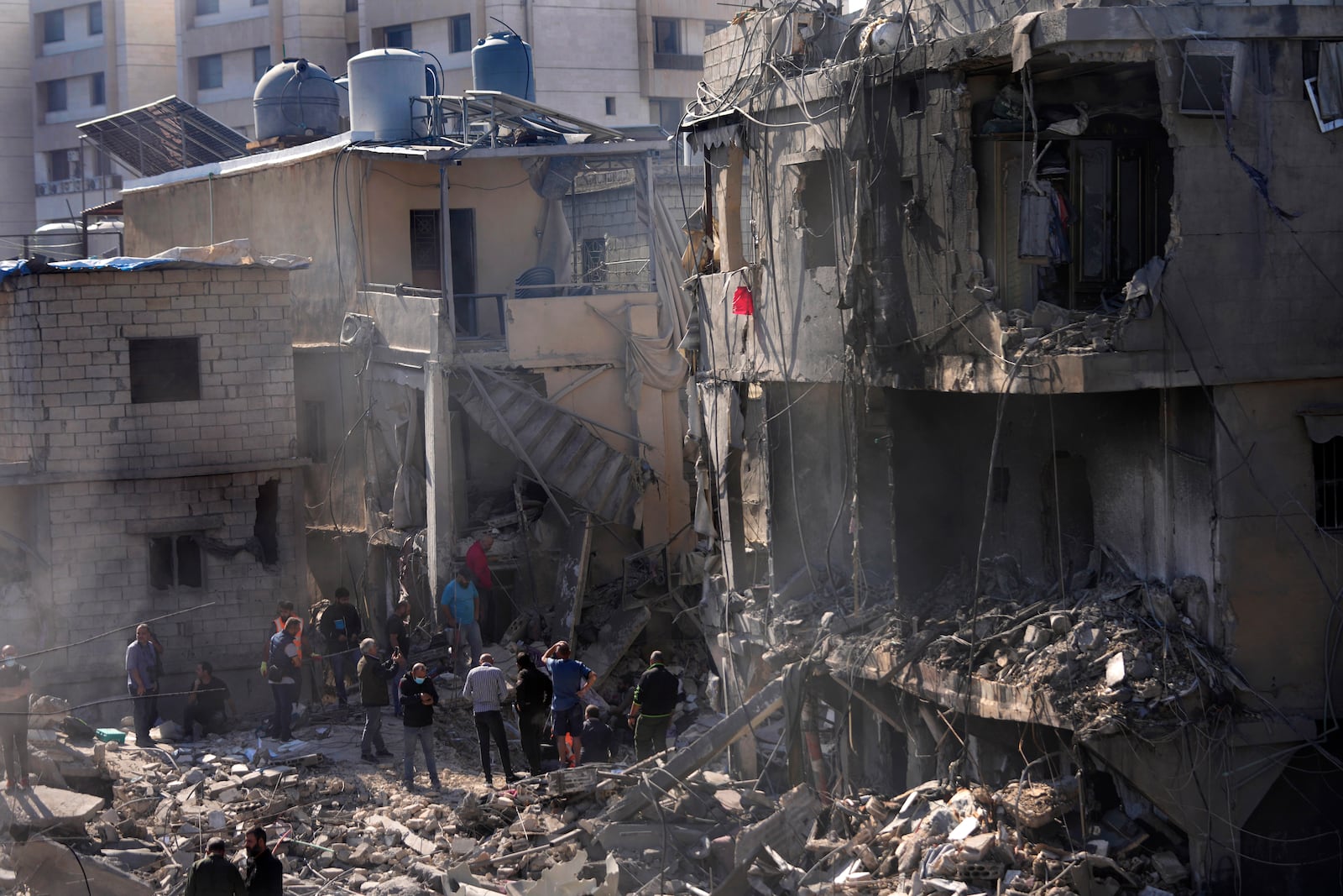 Rescue workers and civilians search for victims between the rubble of destroyed buildings at a popular neighbourhood that was hit Monday night by Israeli airstrikes, south of Beirut, Lebanon, Tuesday, Oct. 22, 2024. (AP Photo/Hussein Malla)