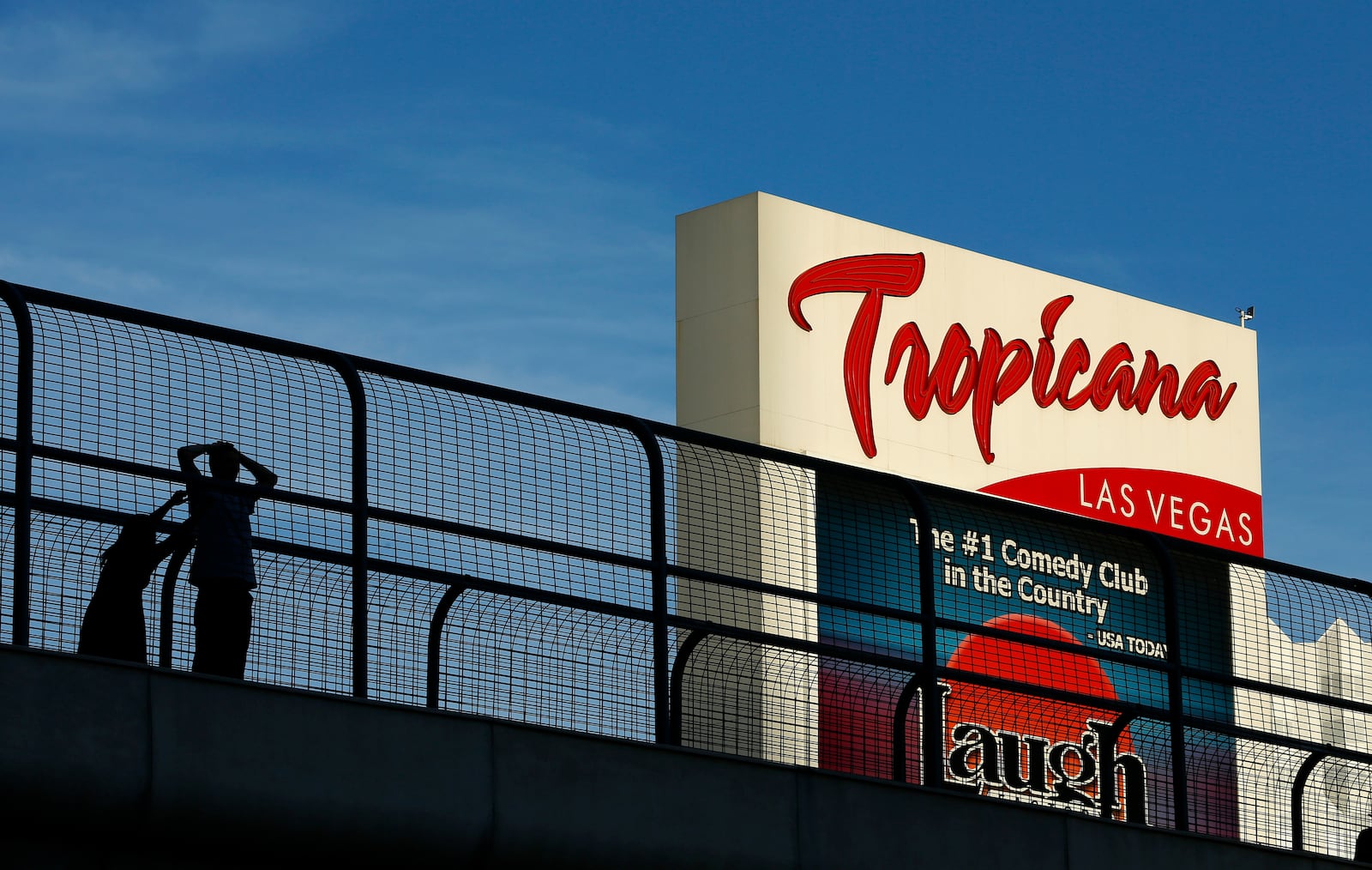 FILE - People stand on a pedestrian bridge by the Tropicana hotel and casino, Aug. 4, 2015, in Las Vegas. (AP Photo/John Locher, File)