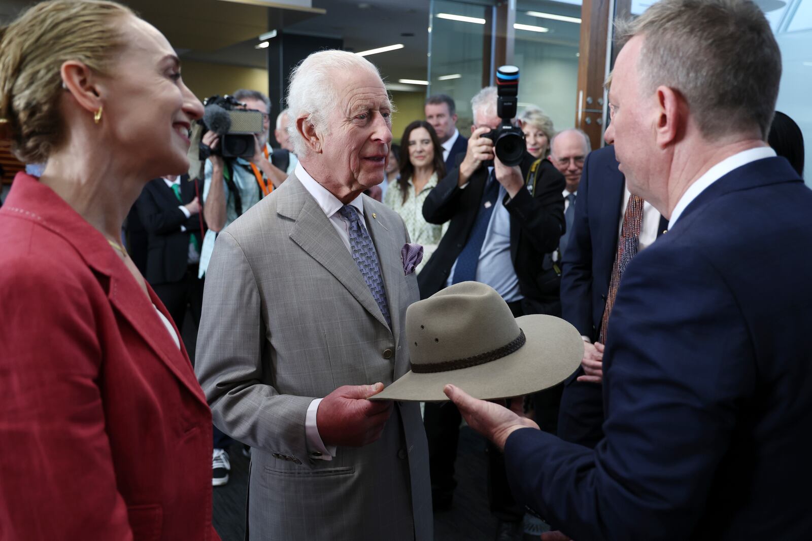 Britain's King Charles III, center, receives a bush hat as a gift from co-medical directors Georgina Long, left, and Richard Scoyler, right, during his visit to the Melanoma Institute of Australia on Tuesday Oct. 22, 2024 in Sydney, Australia. (David Gray/Pool Photo via AP)