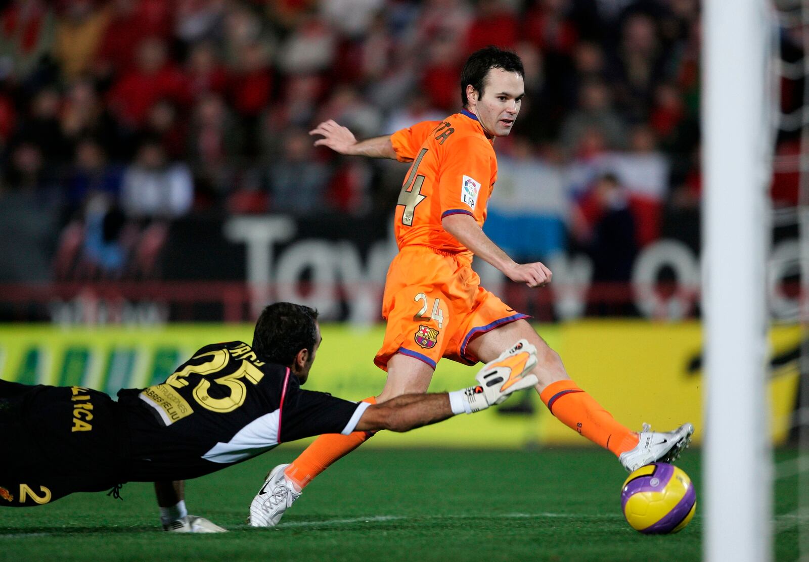 FILE - Barcelona's Andres Iniesta, right, scores against RCD Mallorca goalkeeper Antoni Prats during their Spanish League soccer match at Son Moix Stadium in the Balearic island of Mallorca, Spain, on Nov. 19, 2006. Andres Iniesta who scored Spain's World Cup-winning goal in 2010 and was one of the key players who made Barcelona's tiki-taka thrive for so long, announced his retirement from soccer on Tuesday. (AP Photo/Bernat Armangue, File)