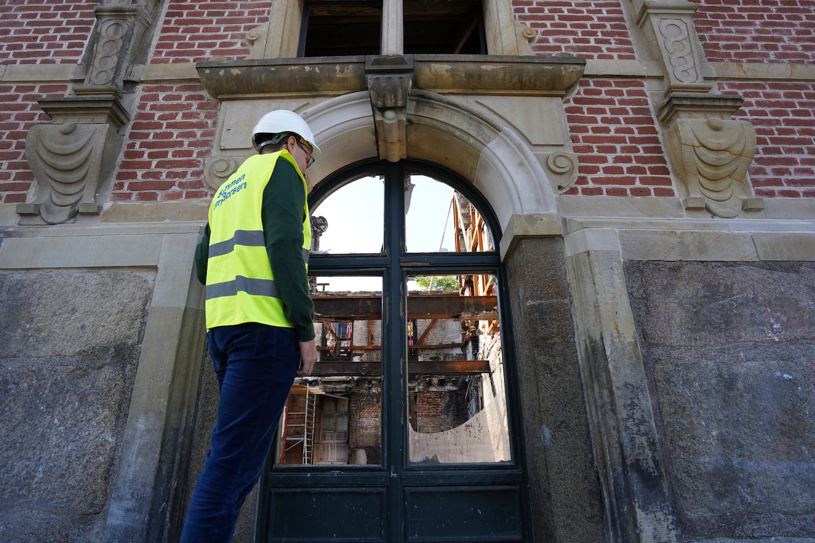 Lars Daugaard Jepsen, head of reconstruction at Denmark's Chamber of Commerce, peers through a window at Copenhagen's Old Stock Exchange building in Copenhagen, Denmark, Thursday, Sept. 19, 2024. (AP Photo James Brooks)