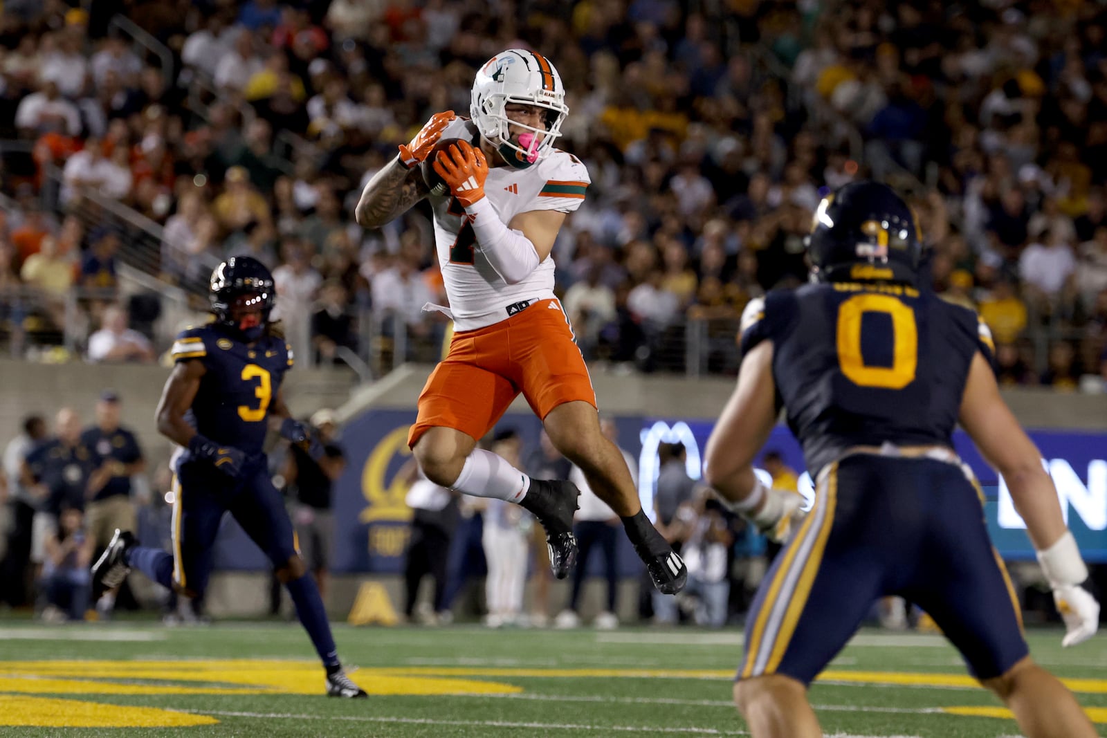 Miami wide receiver Xavier Restrepo (7) catches a pass against California linebacker Cade Uluave (0) during the first half of an NCAA college football game in Berkeley, Calif., Saturday, Oct. 5, 2024. (AP Photo/Jed Jacobsohn)