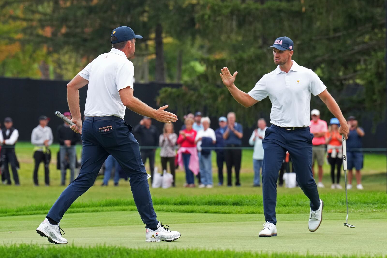 United States team members Keegan Bradley, left, and Wyndham Clark, right, react after Bradley sank a long putt on the 13th green during a first-round four-ball match at the Presidents Cup golf tournament at the Royal Montreal Golf Club in Montreal, Thursday, Sept. 26, 2024. (Nathan Denette/The Canadian Press via AP)