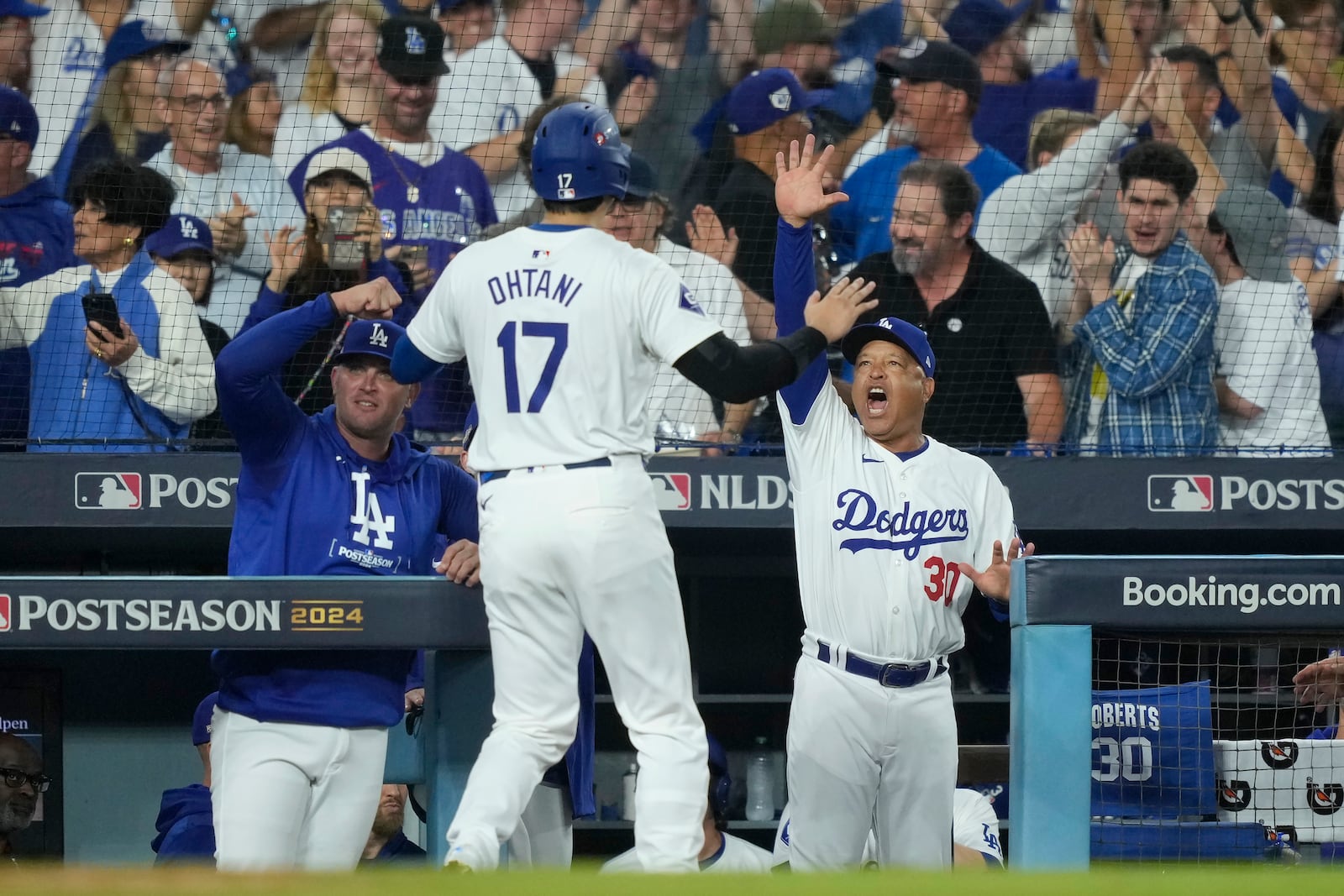 Los Angeles Dodgers' Shohei Ohtani (17) celebrates with manager Dave Roberts, middle right, after Ohtani scored on a single by Teoscar Hernández during the fourth inning in Game 1 of baseball's NL Division Series against the San Diego Padres, Saturday, Oct. 5, 2024, in Los Angeles. (AP Photo/Mark J. Terrill)