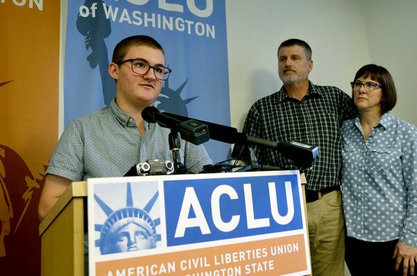 FILE - Paxton Enstad, left, speaks during a news conference about a lawsuit filed over refusal by an insurance plan to cover his gender-reassignment surgery, accompanied by his parents, Cheryl and Mark Enstad, Thursday, Oct. 5, 2017, in Seattle. (AP Photo/Elaine Thompson, File)