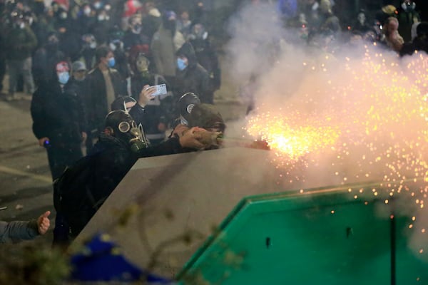 Demonstrators fire a firecracker towards police during a rally against the government's decision to suspend negotiations on joining the European Union for four years, outside the parliament's building in Tbilisi, Georgia, early Sunday, Dec. 1, 2024. (AP Photo/Zurab Tsertsvadze)