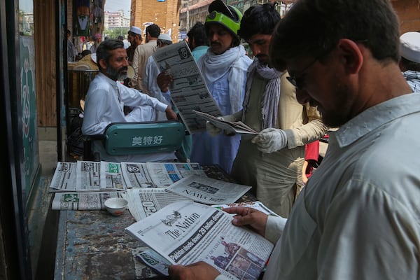 People read morning newspapers covering front page story about Pakistan and India military tension, at a stall in Peshawar, Pakistan, Friday, May 9, 2025. (AP Photo/Muhammad Sajjad)