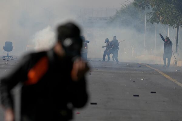 Supporters of imprisoned former premier Imran Khan’s Pakistan Tehreek-e-Insaf party, throw stone as police fire tear gas shell to disperse them during clashes, in Islamabad, Pakistan, Tuesday, Nov. 26, 2024. (AP Photo/Anjum Naveed)