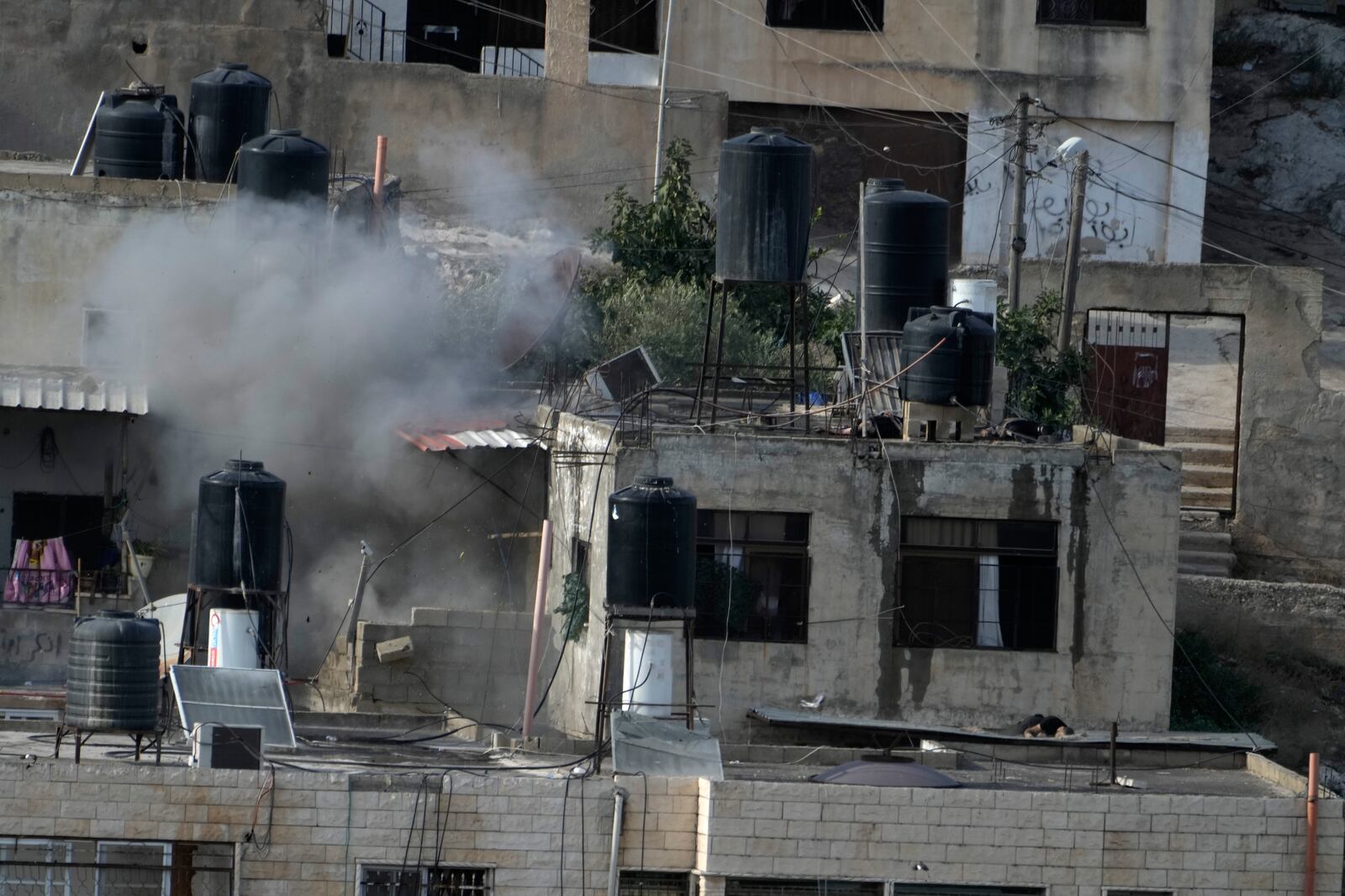 EDS NOTE: GRAPHIC CONTENT - An explosion is seen with three bodies lie motionless on rooftops in the West Bank town of in the West Bank town of Qatabiya during a raid, Thursday, Sept. 19, 2024. (AP Photo/Majdi Mohammed)