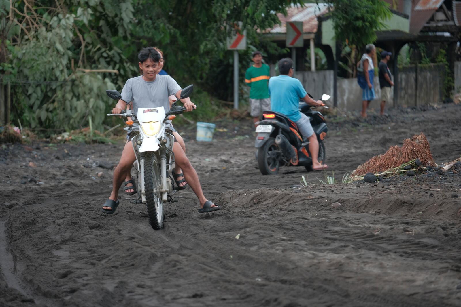 Residents negotiate a road covered with volcanic mud that flowed down from Mayon volcano after heavy rains caused by Tropical Storm Trami hit Guinobatan town, Albay province, Philippines on Wednesday Oct. 23, 2024. (AP Photo/John Michael Magdasoc)