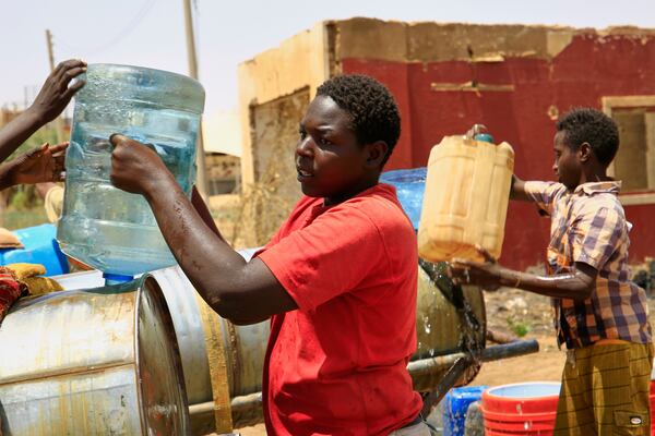 People fill a container by water due to water outages in Khartoum, Sudan, Sunday, May 25, 2025. (AP Photo)