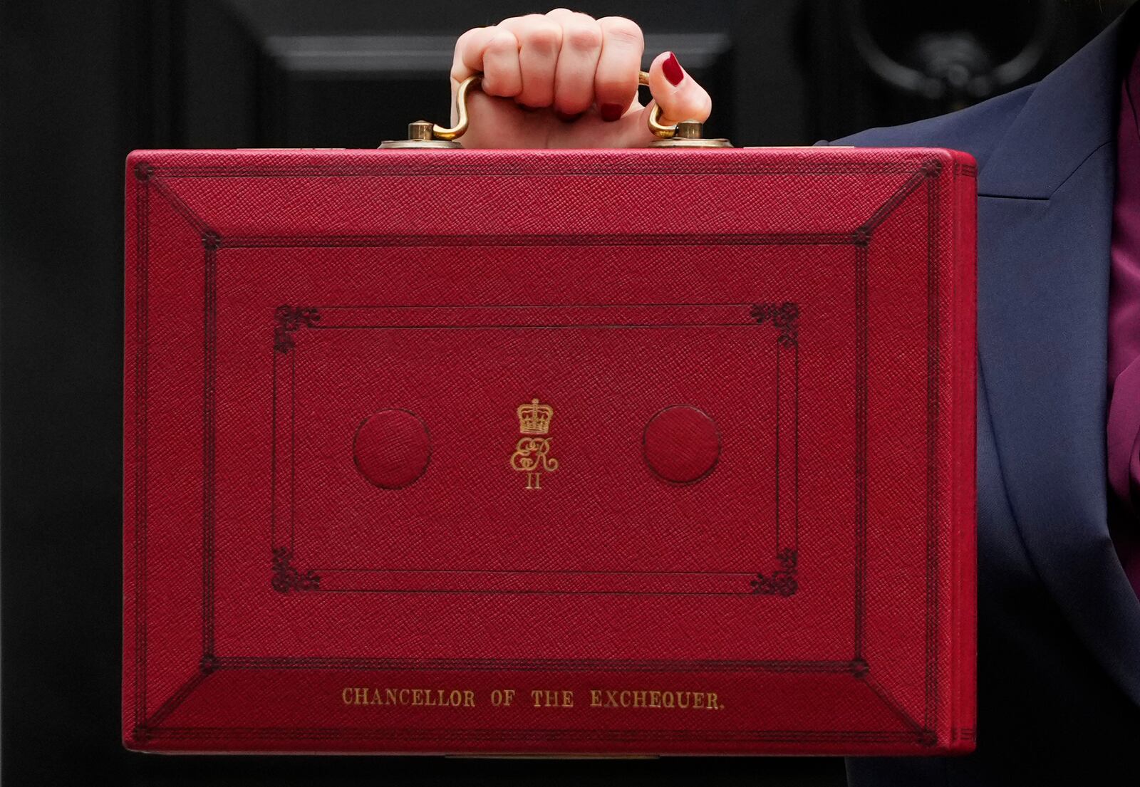 Britain's Chancellor of the Exchequer, Rachel Reeves, holds up the traditional red ministerial box containing her budget speech, as she poses for the media outside No 11 Downing Street, before departing to the House of Commons to deliver the budget in London, Wednesday, Oct. 30, 2024. (AP Photo/Kirsty Wigglesworth)