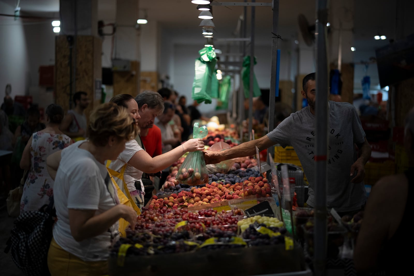 A woman buys fruit in a local market in Haifa, Israel, on Aug. 16, 2024. (AP Photo/Leo Correa)