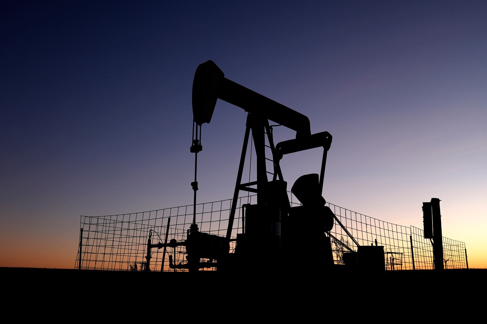 A pumpjack operates at dawn in a pasture, Monday, Sept. 30, 2024, near Hays, Kan. (AP Photo/Charlie Riedel)