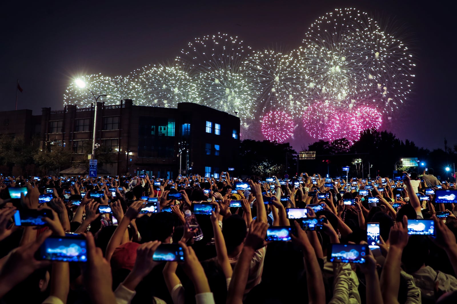 FILE - People use smartphones to film fireworks exploding at Tiananmen Square as part of a gala evening commemorating the 70th anniversary of the founding of Communist China light up the sky in Beijing, Tuesday, Oct. 1, 2019. (AP Photo/Andy Wong, File)