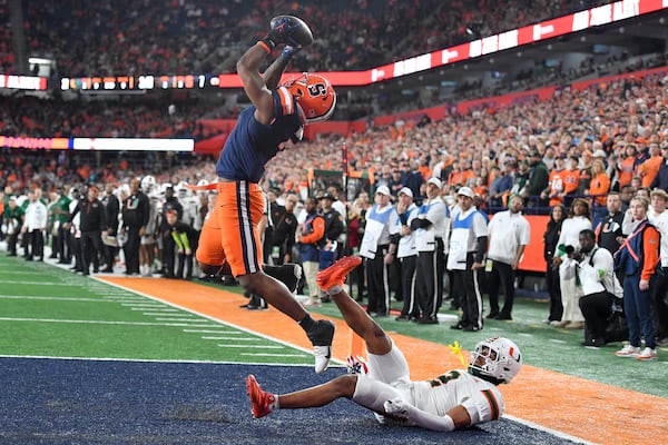 Syracuse wide receiver Jackson Meeks, left, catches a touchdown pass over Miami defensive back Daryl Porter Jr. (2) during the first half of an NCAA football game on Saturday, Nov. 30, 2024 in Syracuse, N.Y. (AP Photo/Adrian Kraus)