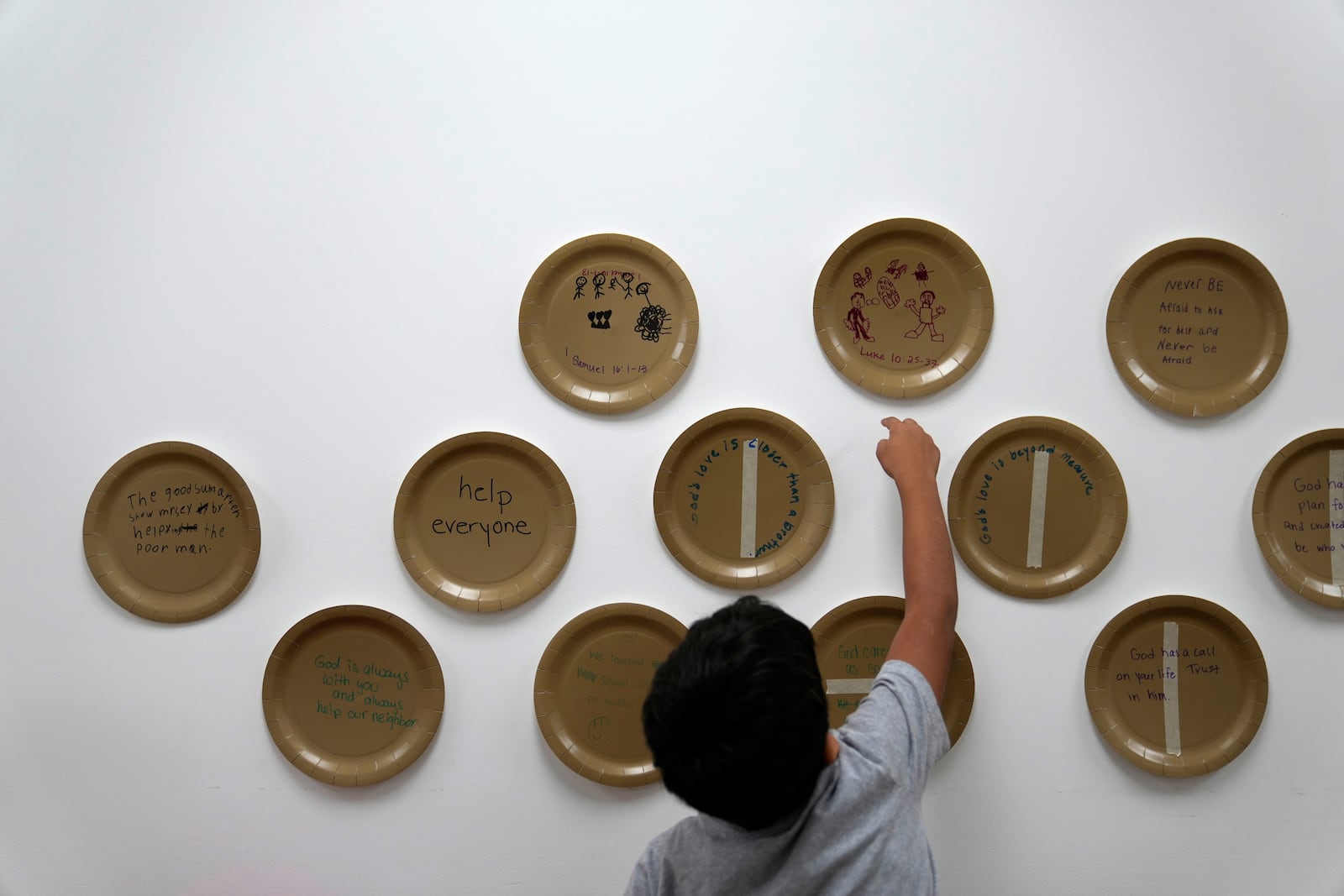 A child reaches for a drawing on a plate he completed inside St. Michael the Archangel Catholic church in Erwin, Tenn., on Friday, Oct. 4, 2024, in the aftermath of Hurricane Helene. (AP Photo/Jeff Roberson)