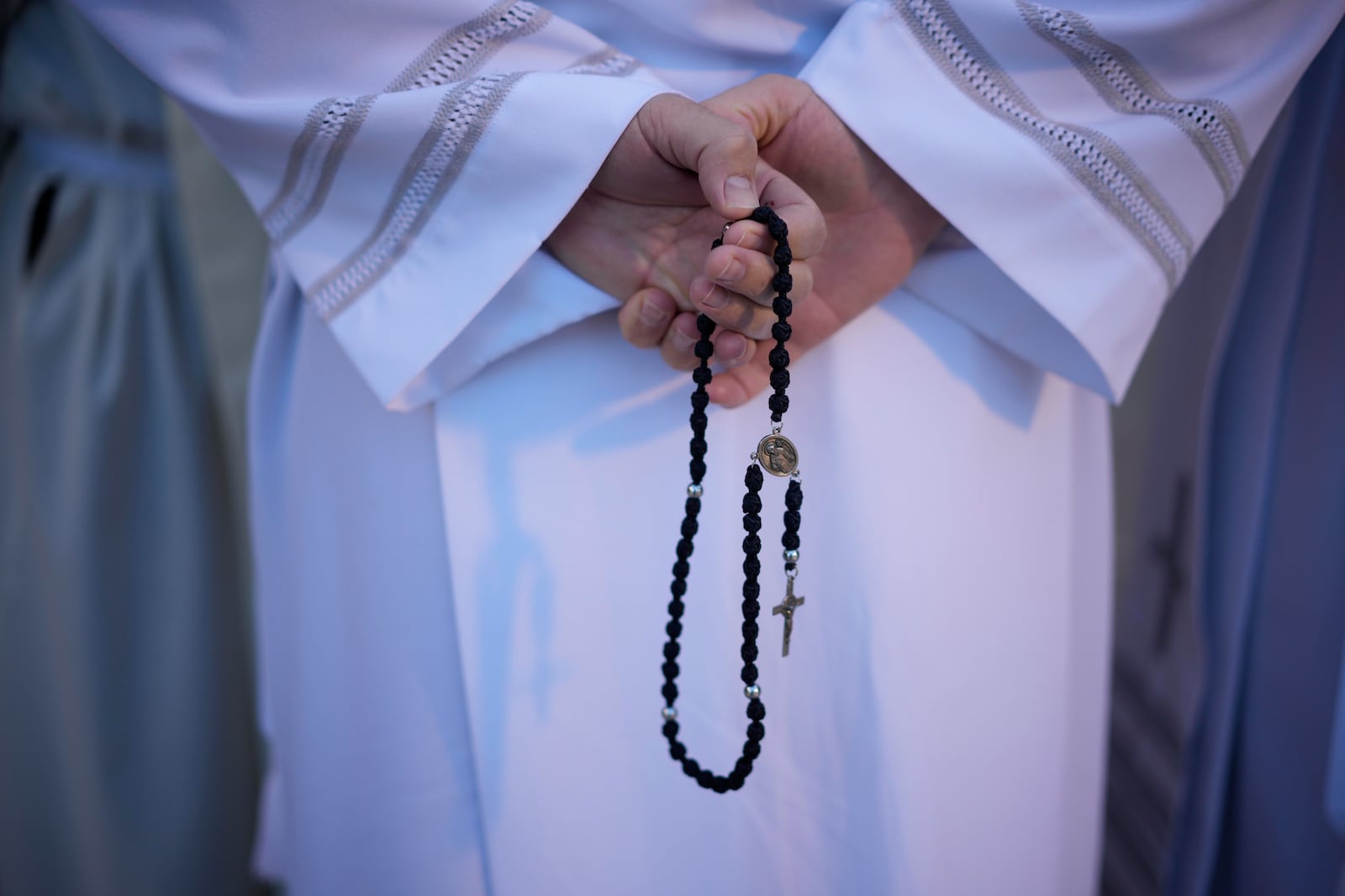 A priest holds a rosary prior to the start of a mass presided by Pope Francis at King Baudouin Stadium, in Brussels Sunday, Sept. 29, 2024. (AP Photo/Andrew Medichini)