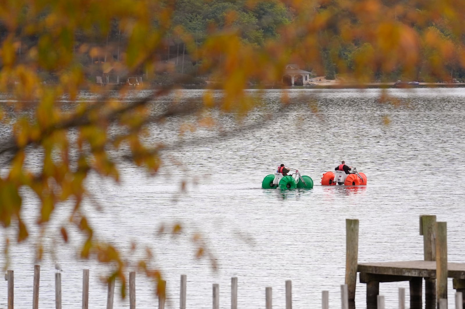 Leaves on trees display bright colors as people using water craft float on Meredith Bay, in Meredith, N.H., Wednesday, Oct. 2, 2024. (AP Photo/Steven Senne)