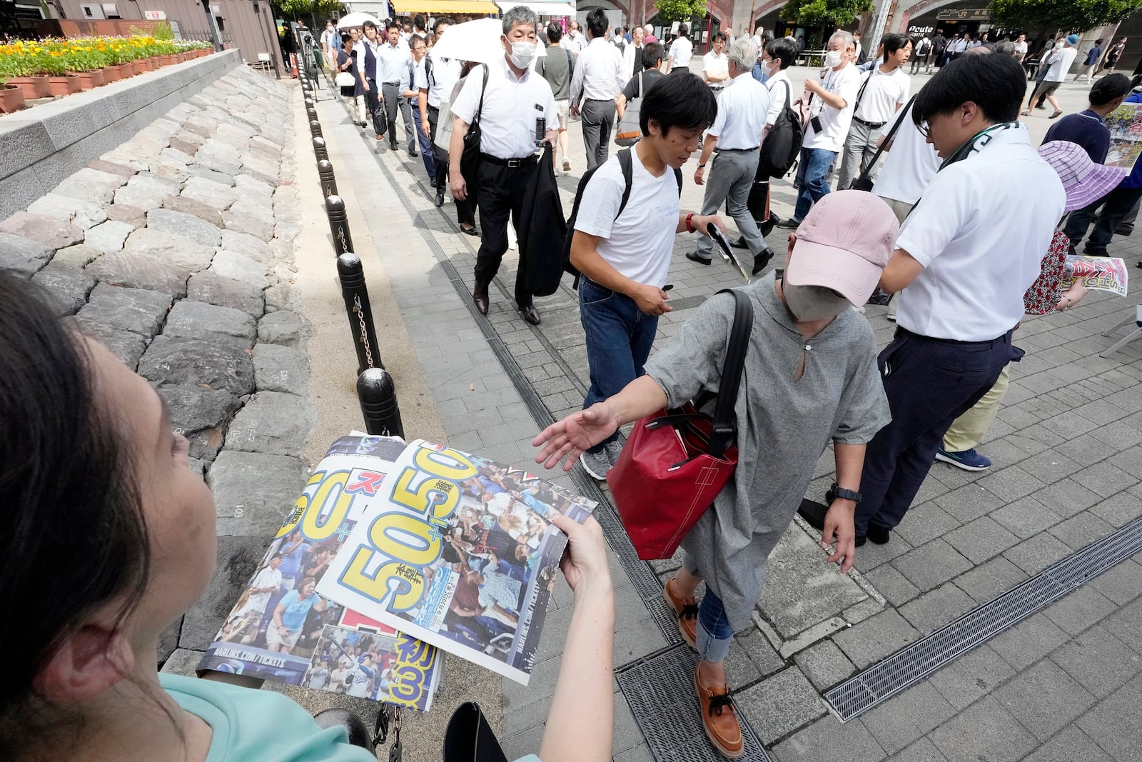 Pedestrians line up to obtain an extra edition of the Sports Nippon newspaper reporting on the Los Angeles Dodgers' Shohei Ohtani becoming the first player in major league history with 50 home runs and 50 stolen bases in a season, Friday, Sept. 20, 2024, in Tokyo. (AP Photo/Eugene Hoshiko)