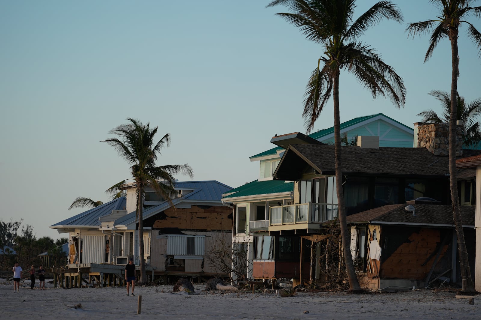 People survey damage to beachfront homes, many of which had their ground floor level washed out, following Hurricane Milton, on Manasota Key, Fla., Saturday, Oct. 12, 2024. (AP Photo/Rebecca Blackwell)