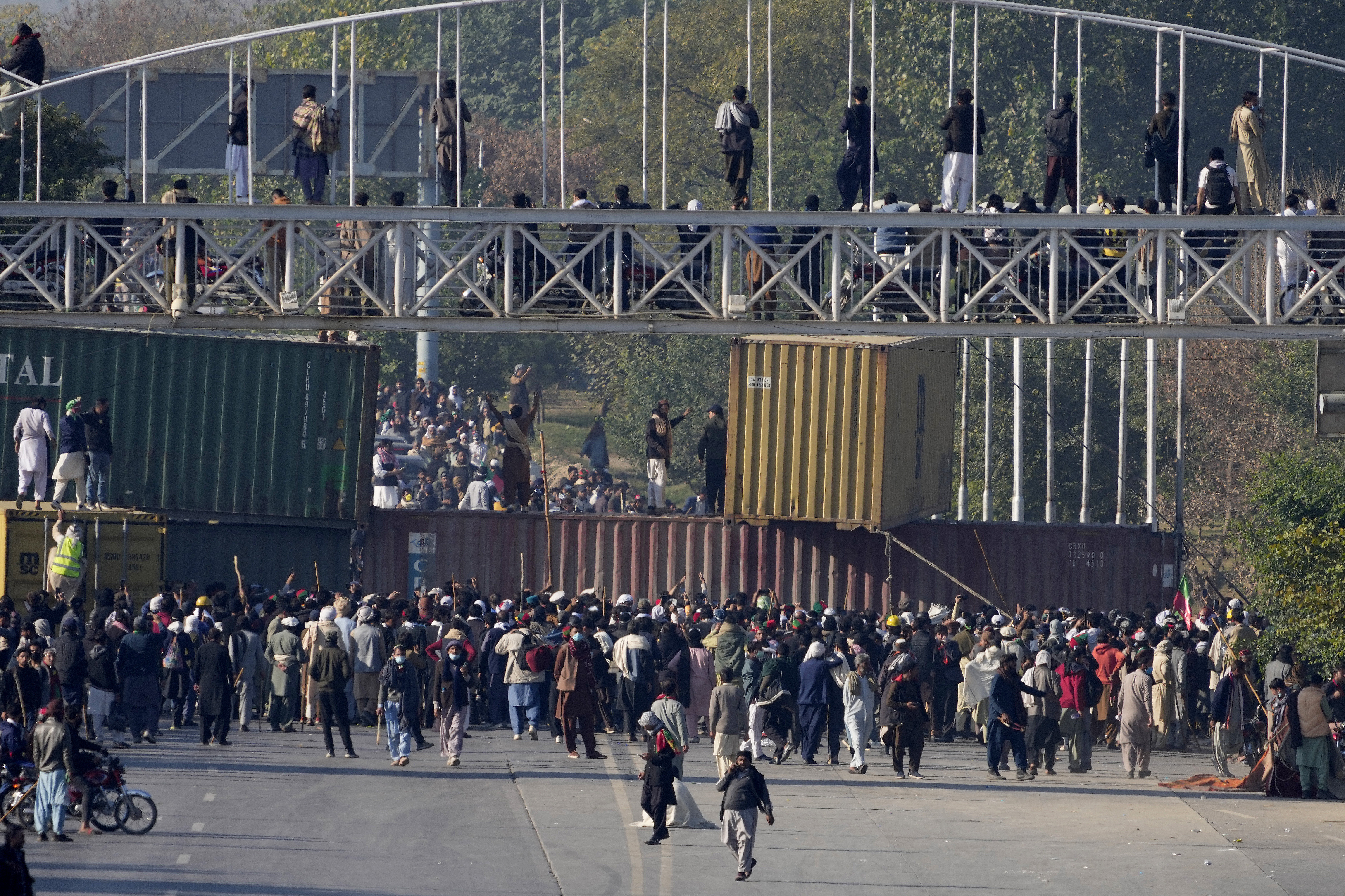 Supporters of imprisoned former premier Imran Khan's Pakistan Tehreek-e-Insaf party, gather to remove shipping container to clear way for their rally demanding Khan's release, in Islamabad, Pakistan, Tuesday, Nov. 26, 2024. (AP Photo/Anjum Naveed)