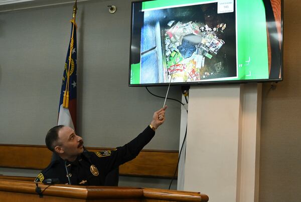 Athens-Clarke County police officer Zachary Davis points out the jacket he collected from a dumpster on photograph as he testifies on the witness stand during a trial of Jose Ibarra, accused of killing a Georgia nursing student earlier this year, at Athens-Clarke County Superior Court, Friday, Nov. 15, 2024, in Athens, Ga. (Hyosub Shin/Atlanta Journal-Constitution via AP, Pool)