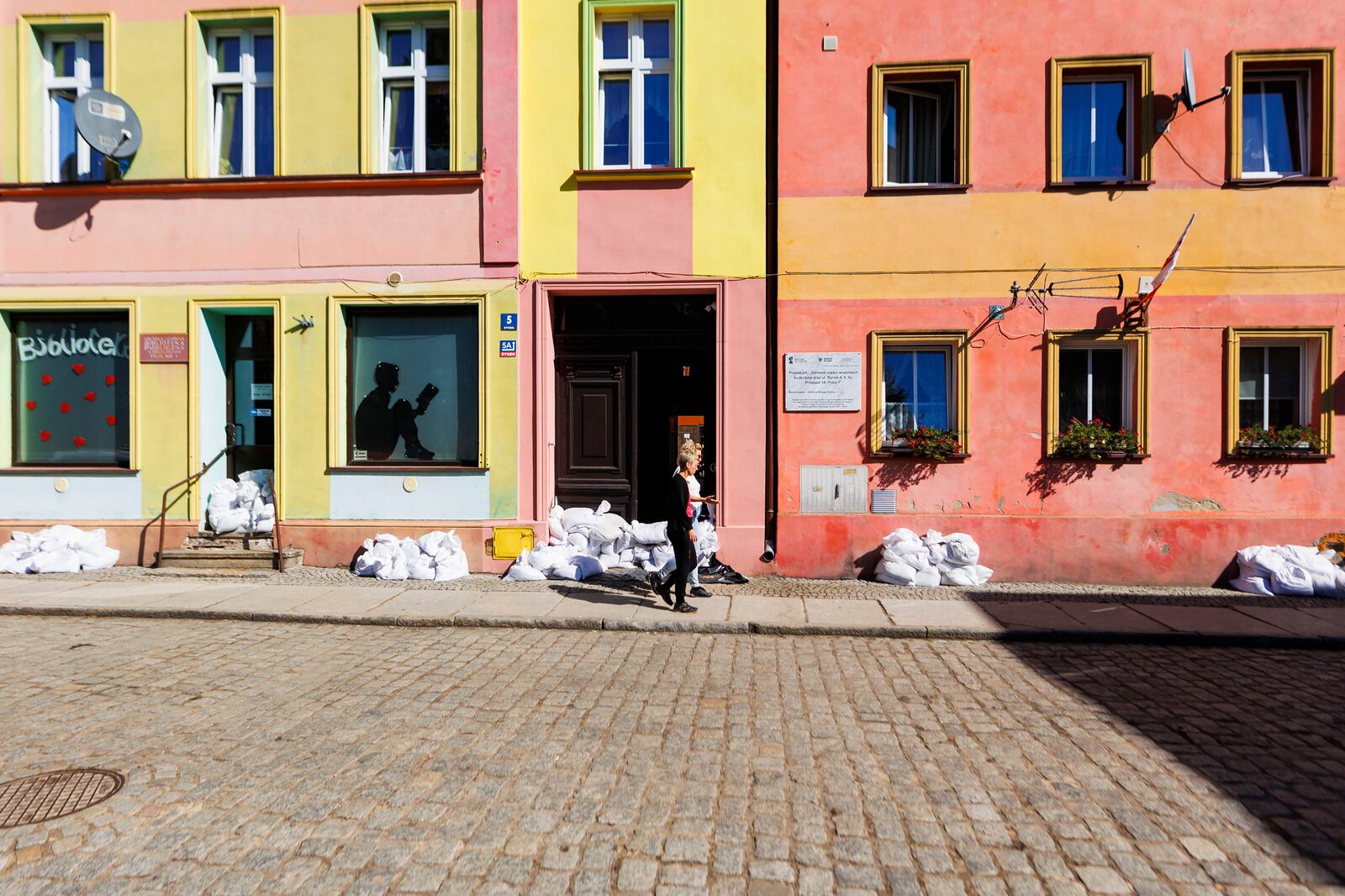 A women walks past sandbags set to protect from the high waters of the Oder River, in Brzeg Dolny, Poland, Friday Sept. 20, 2024. (AP Photo/Krzysztof Zatycki)