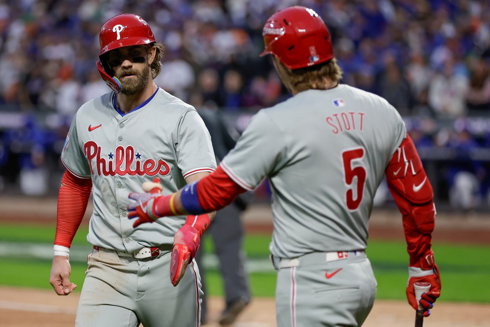 Philadelphia Phillies' Bryce Harper is congratulated by Bryson Stott (5) after scoring on an error by New York Mets third baseman Mark Vientos during the fourth inning of Game 4 of the National League baseball playoff series, Wednesday, Oct. 9, 2024, in New York. (AP Photo/Adam Hunger)