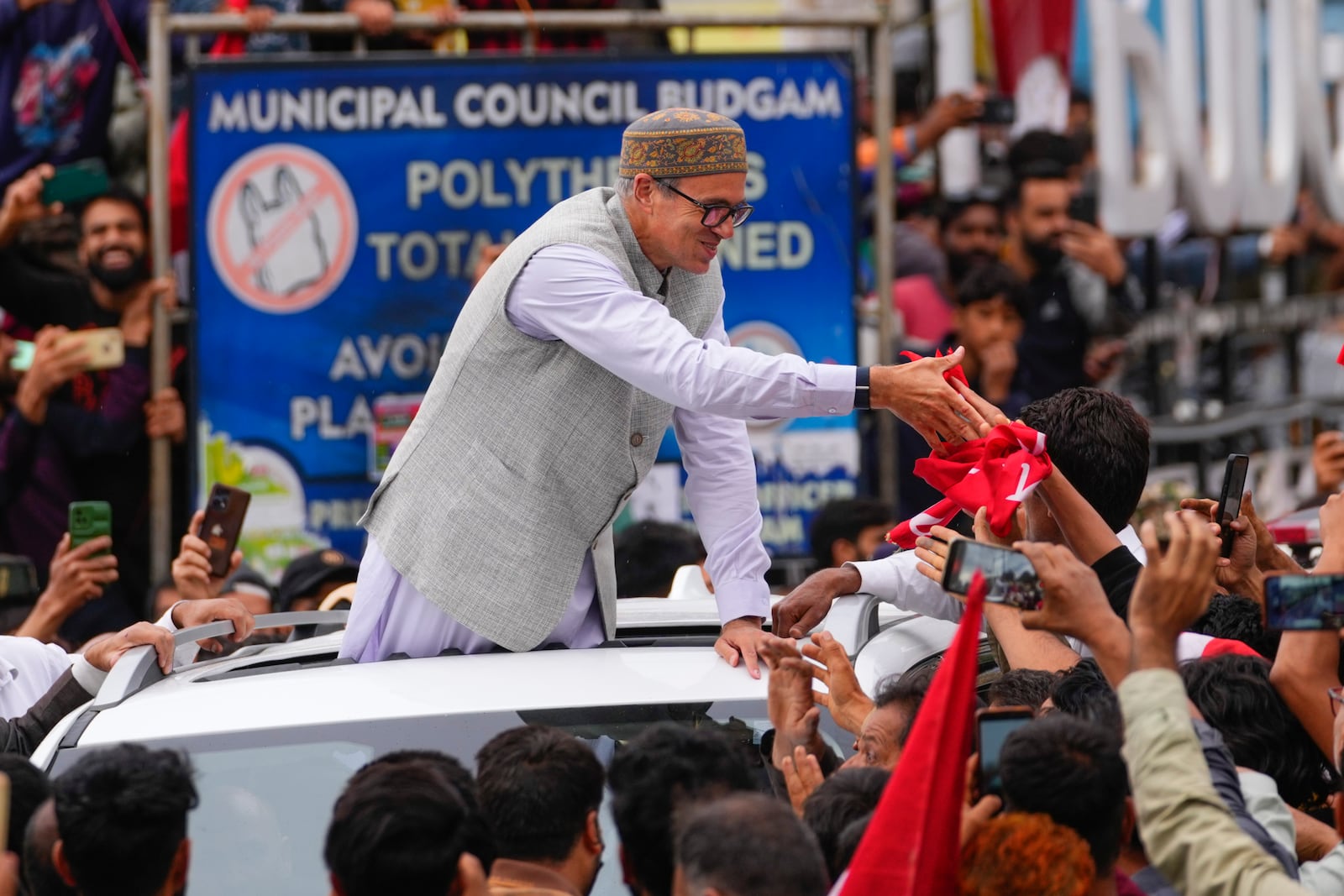 Jammu and Kashmir National Conference (JKNC) party leader Omar Abdullah, standing on car shakes hands with supporters as he celebrates his victory in the election for a local government in Indian controlled Kashmir, Budgam, Tuesday, Oct. 8, 2024. (AP Photo/Dar Yasin)