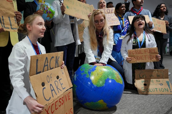 Activist Ann Carlotta Oltmanns, center, pretends to resuscitate Earth with others during a demonstration at the COP29 U.N. Climate Summit, Monday, Nov. 18, 2024, in Baku, Azerbaijan. (AP Photo/Peter Dejong)