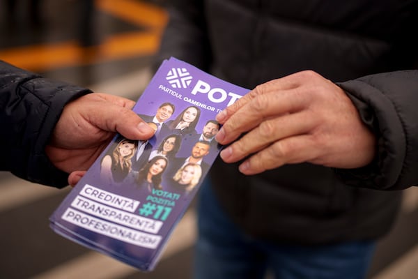 A man distributes leaflets of the Young People's Party or POT, which has backed Calin Georgescu, an independent candidate who won the first round of presidential elections, in Bucharest, Romania, Friday, Nov. 29, 2024. (AP Photo/Andreea Alexandru)