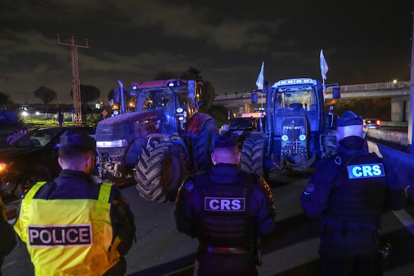 Police officers stand in front of tractors on a blocked highway in Velizy-Villacoublay, outside Paris, Sunday Nov. 17, 2024. (AP Photo/Michel Euler)