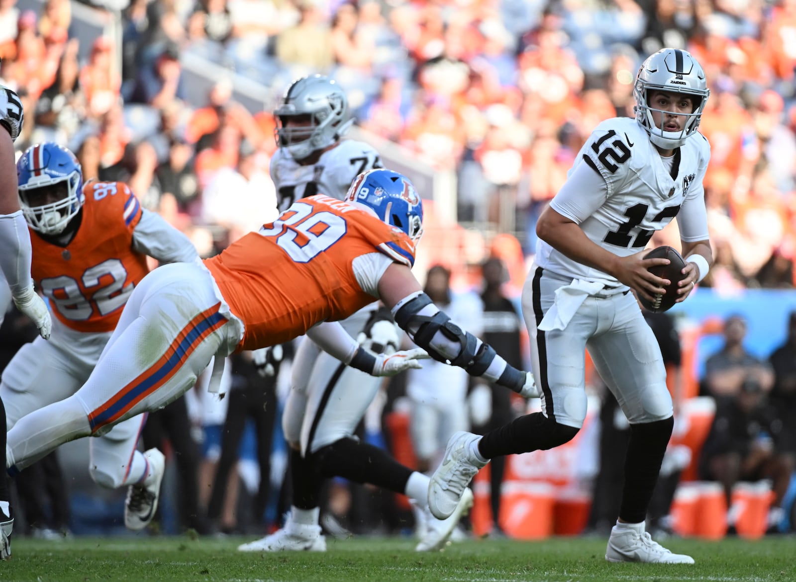 Las Vegas Raiders quarterback Aidan O'Connell, right, avoids Denver Broncos defensive end Zach Allen in the second half of an NFL football gam,e Sunday, Oct. 6, 2024, in Denver. (AP Photo/Geneva Heffernan)