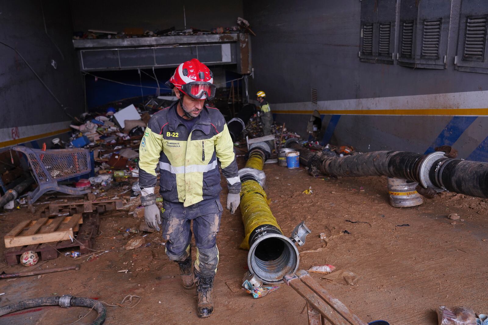 A firefighter works in the entrance of an underground car park in the MN4 shopping centre as rescue workers look for bodies on the outskirts of Valencia, Spain, Monday, Nov. 4, 2024. (AP Photo/Alberto Saiz)