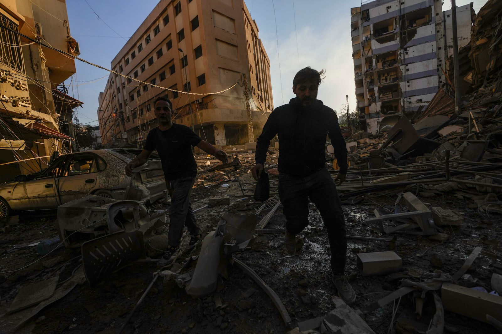 Residents run for cover following an Israeli airstrike in Dahiyeh, Beirut, Lebanon, Friday, Oct. 4, 2024. (AP Photo/Hassan Ammar)