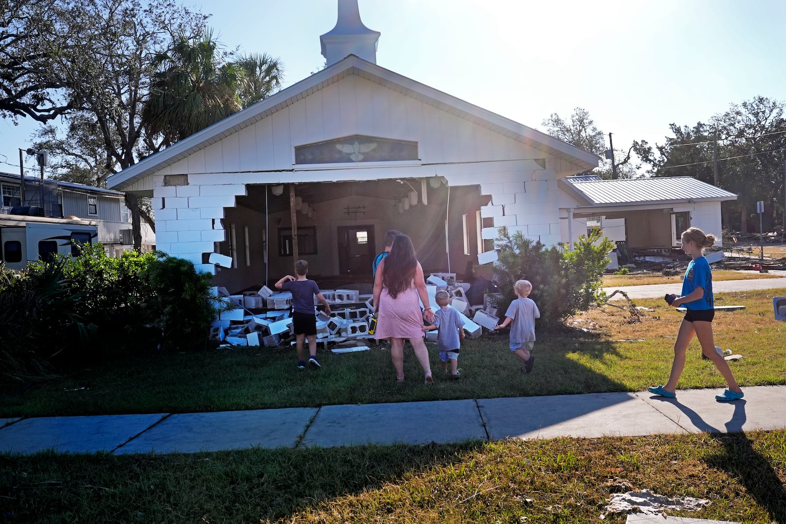 A group from St. Augustine, Fla. that arrived to help storm victims, who did not want to give their names, pray outside the damaged First Baptist Church in the aftermath of Hurricane Helene, in Horseshoe Beach, Fla., Sunday, Sept. 29, 2024. (AP Photo/Gerald Herbert)