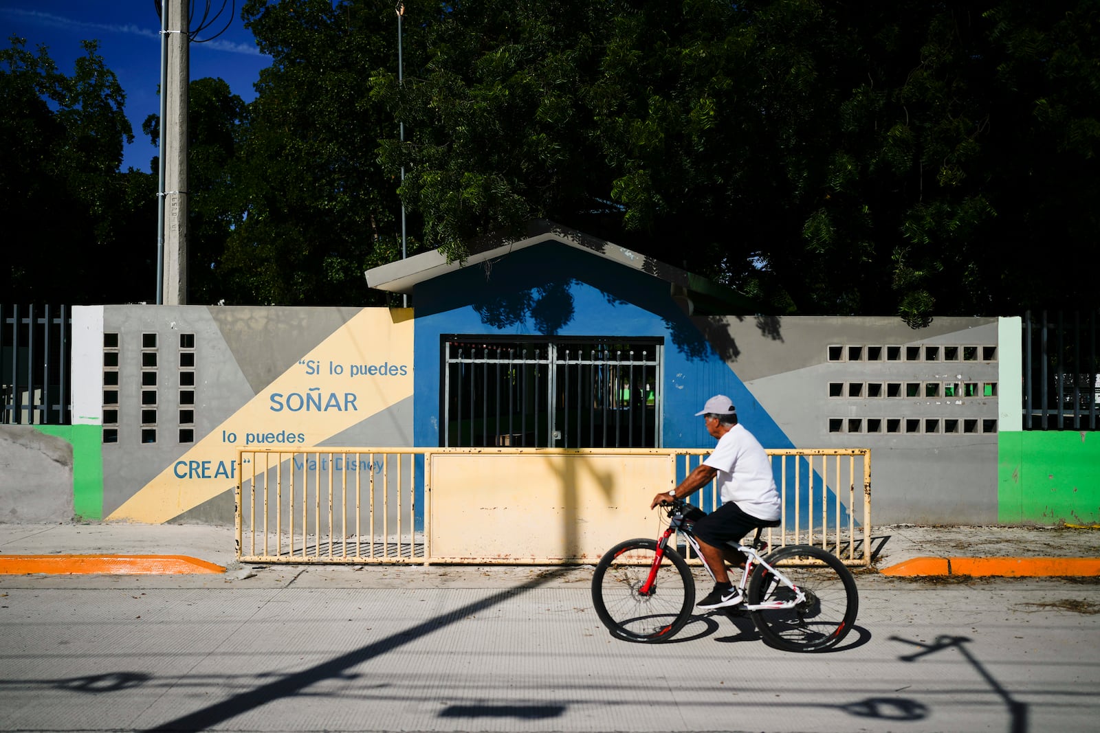 A resident pedals his bicycle past the temporarily closed Lazaro Cardenas elementary school, in Culiacan, Sinaloa state, Mexico, Thursday, Sept. 19, 2024. (AP Photo/Eduardo Verdugo)