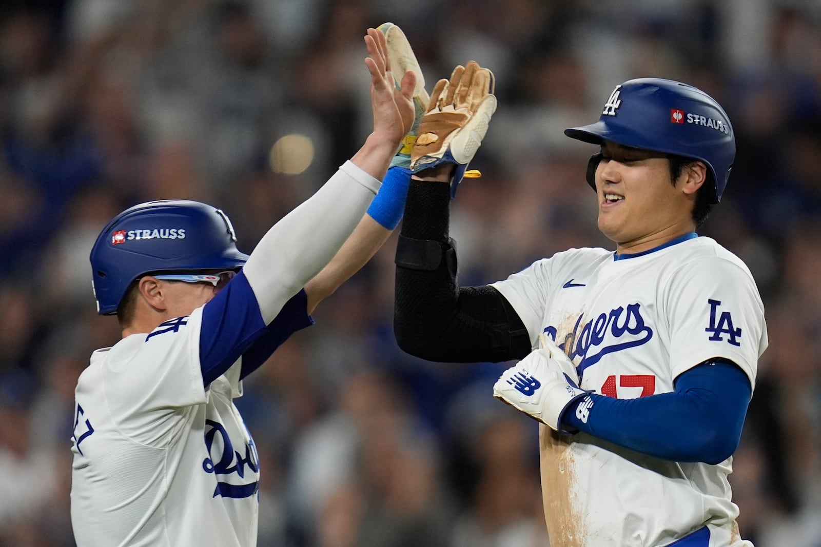 Los Angeles Dodgers' Shohei Ohtani celebrates with Kiké Hernández after scoring on a double by Mookie Betts during the eighth inning in Game 1 of a baseball NL Championship Series against the New York Mets, Sunday, Oct. 13, 2024, in Los Angeles. (AP Photo/Gregory Bull)