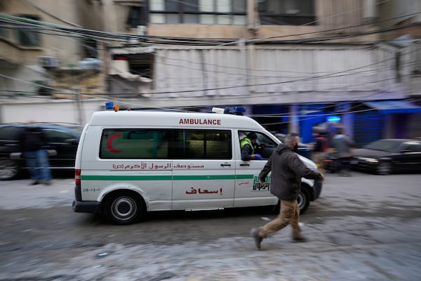 A man runs next to an ambulance arriving at the site of an Israeli airstrike that targeted a building in Beirut, Lebanon, Tuesday, Nov. 26, 2024. (AP Photo/Hassan Ammar)