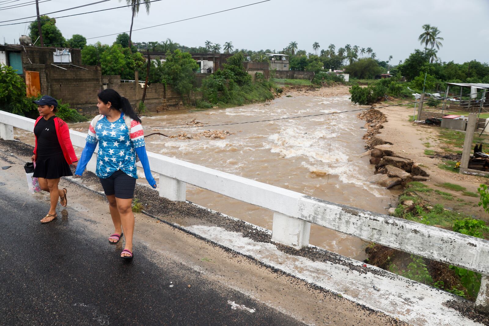 Women walk on a bridge in the aftermath of Hurricane John, in Acapulco, Mexico, Friday, Sept. 27, 2024. (AP Photo/Bernardino Hernandez)