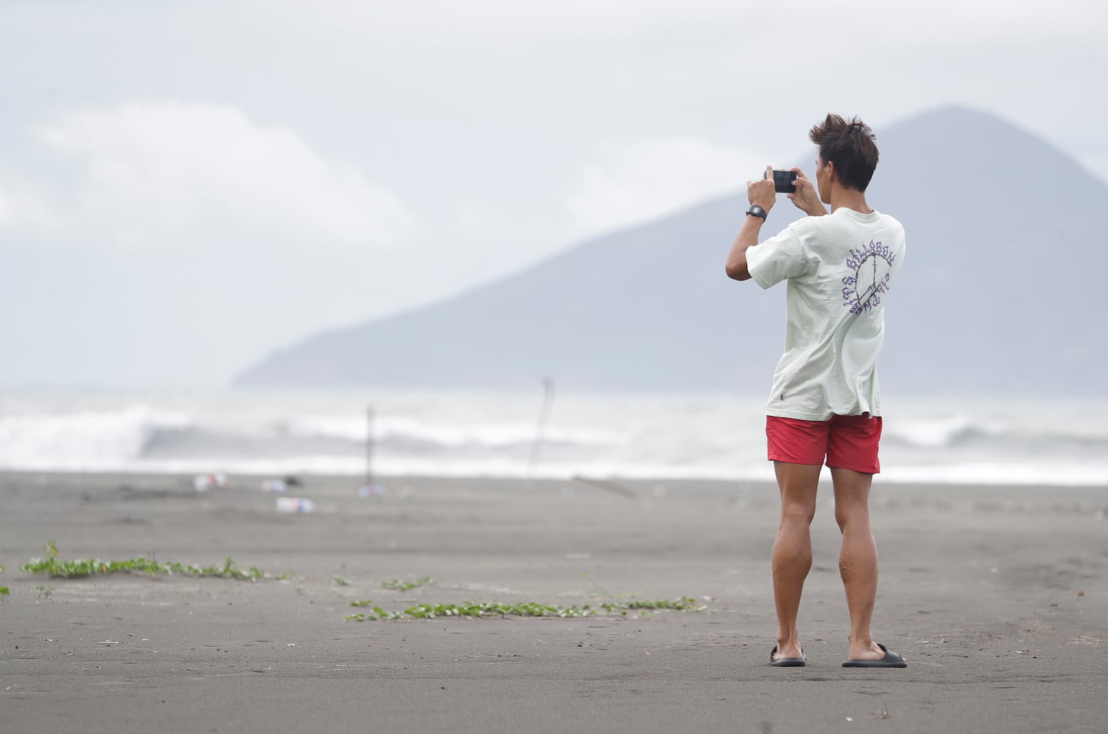 A man takes a photo on a beach as Typhoon Krathon approaches to Taiwan in Yilan County, eastern coast of Taiwan, Tuesday, Oct. 1, 2024. (AP Photo/Chiang Ying-ying)