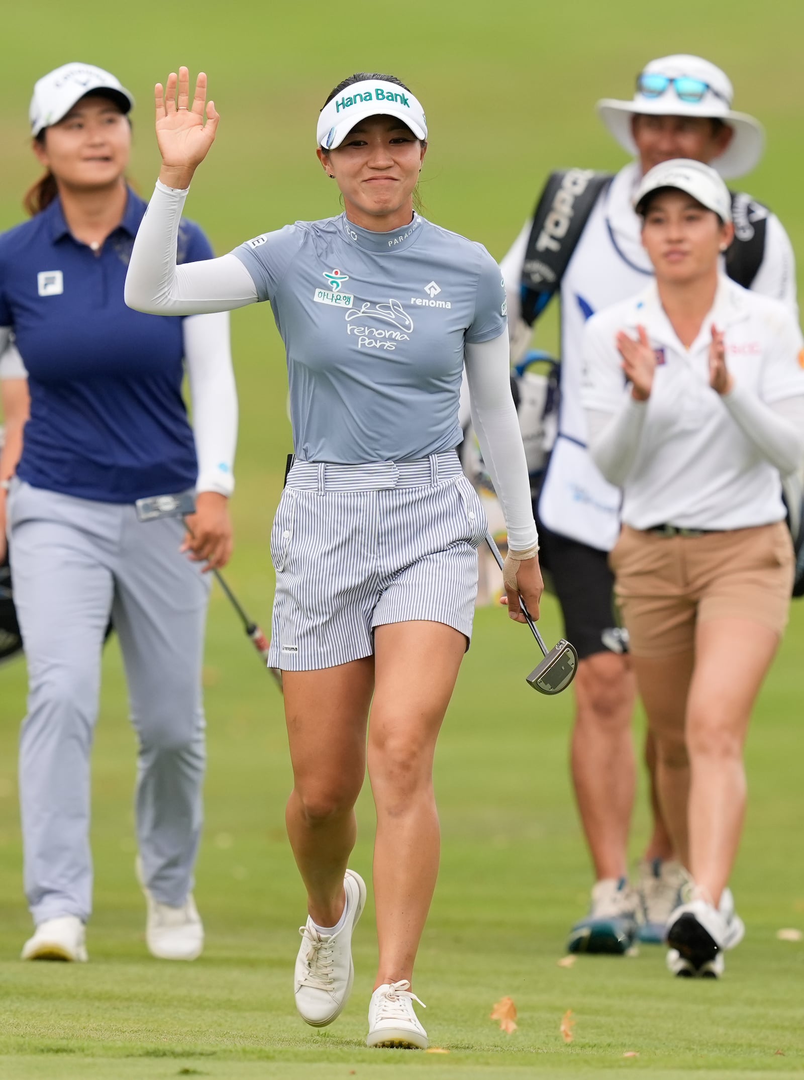 Lydia Ko, center, of New Zealand, center, waves to a cheering crowd as she walks to the 18th hole, followed by Yan Liu, left, of China, and Jeeno Thitikul, front right, of Thailand, during the final round of the LPGA Kroger Queen City Championship golf tournament at TPC River's Bend in Maineville, Ohio, Sunday, Sept. 22, 2024. (AP Photo/Carolyn Kaster)